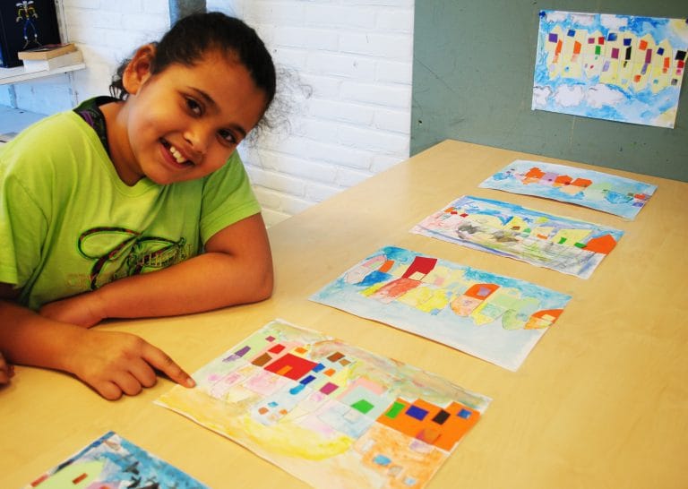 Kunstkabaal in de klas - Meisje met kunstproject. Draagt felgroen tshirt